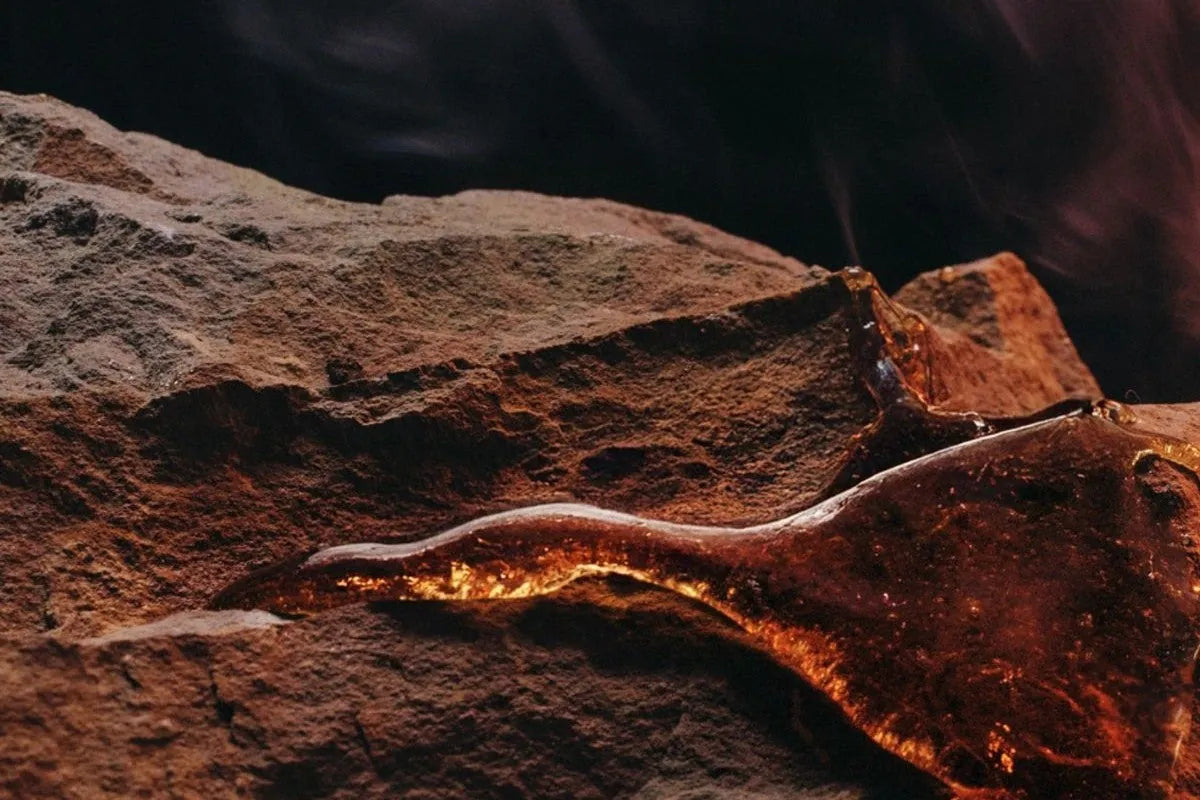 Close-up of a rough amber seam glowing orange within dark weathered rock