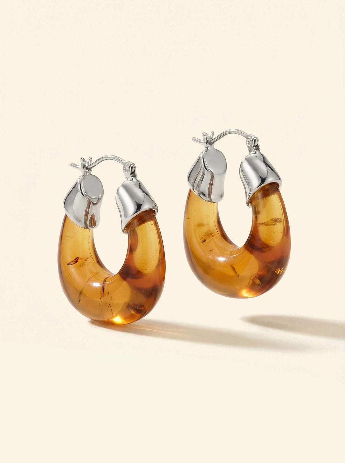 Ember Hoops, pair of translucent amber-coloured hoops with silver-tone caps, angled view