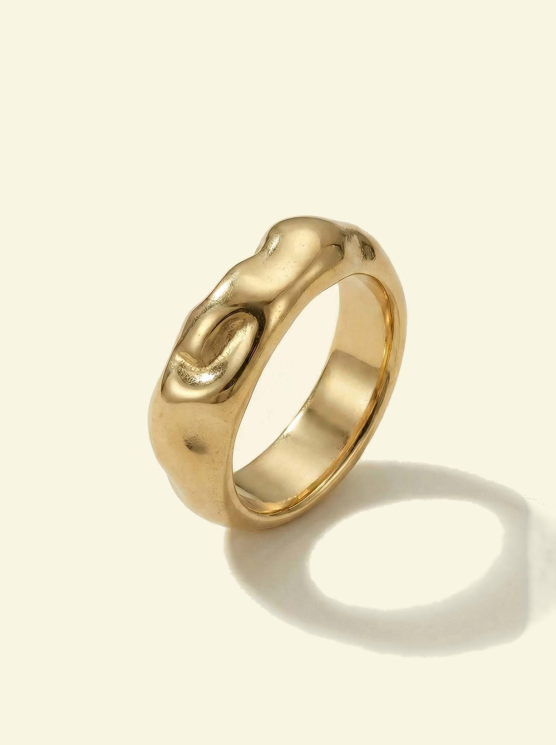 Anvil Ring, gold-tone hammered band at an angle with a round shadow, showing the inside of the band