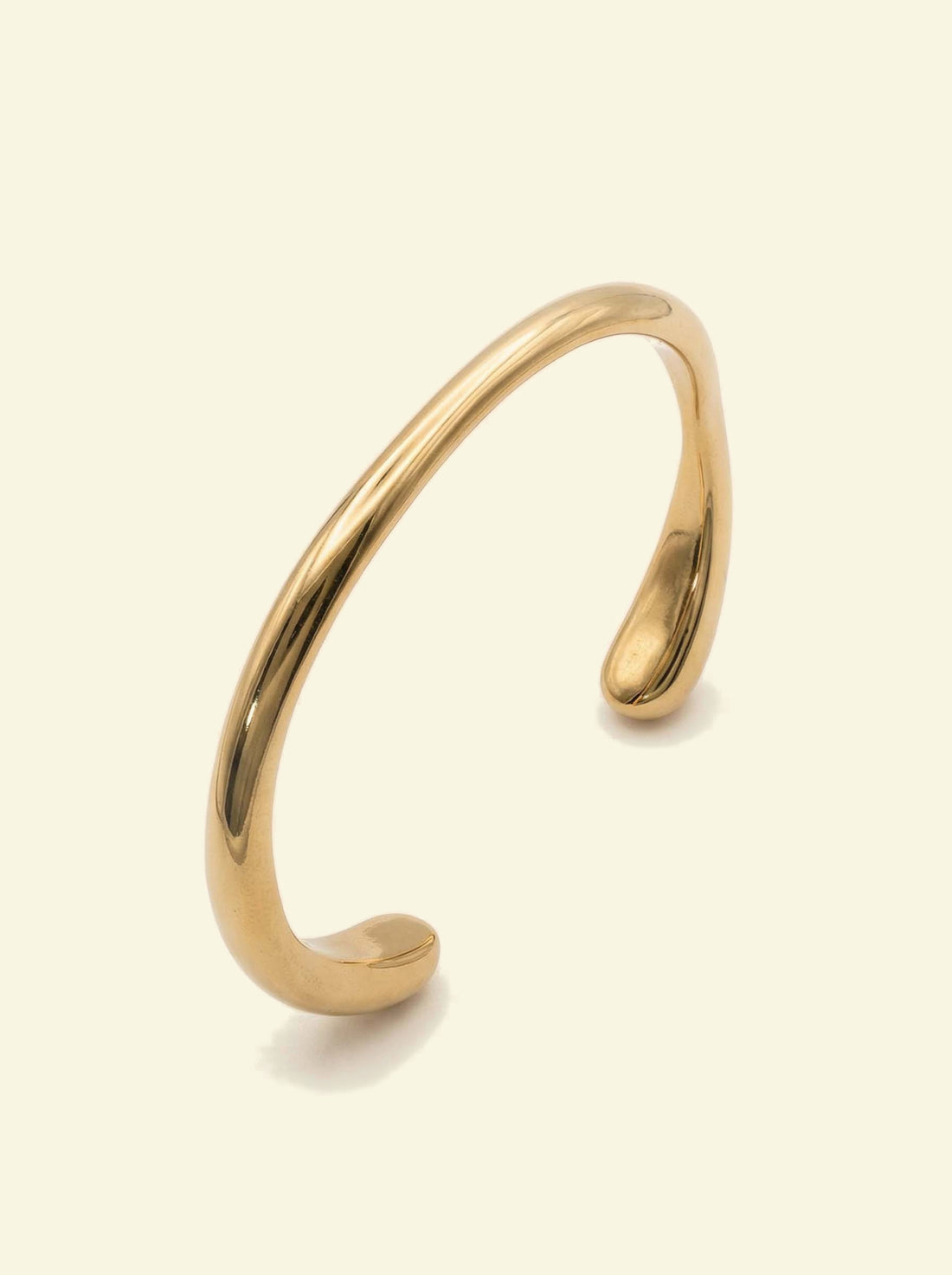 Arc Cuff, gold-tone open cuff seen from a low angle, showing the tapered ends