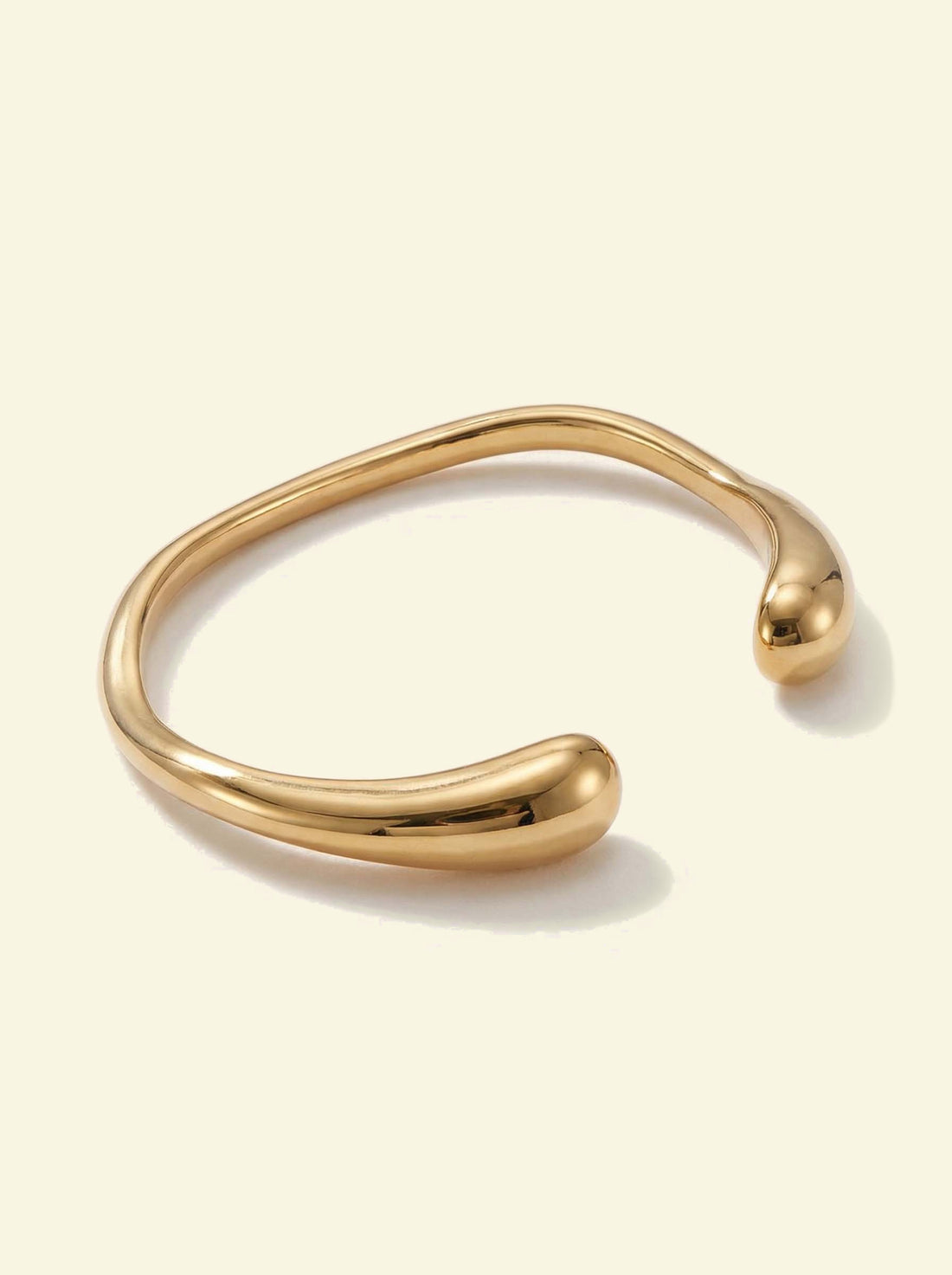 Arc Cuff, gold-tone open cuff with a slightly wavy band and rounded tips, top angle
