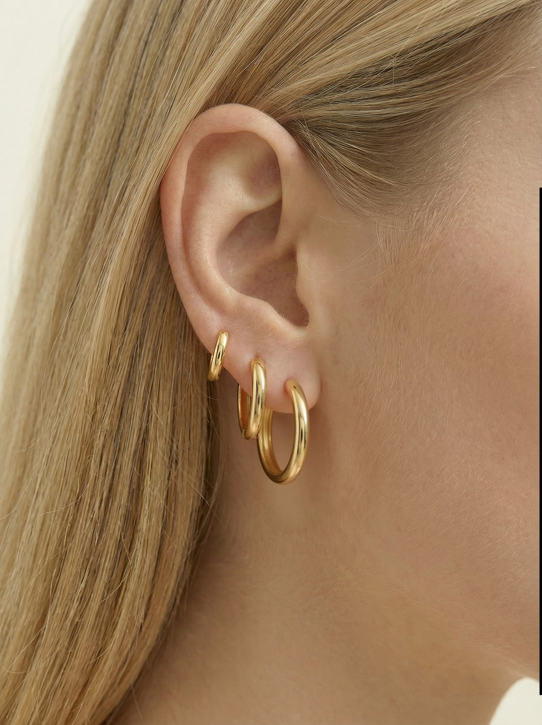 Classic Hoops, three gold-tone hoops of graduated sizes worn together in one woman's ear, side profile