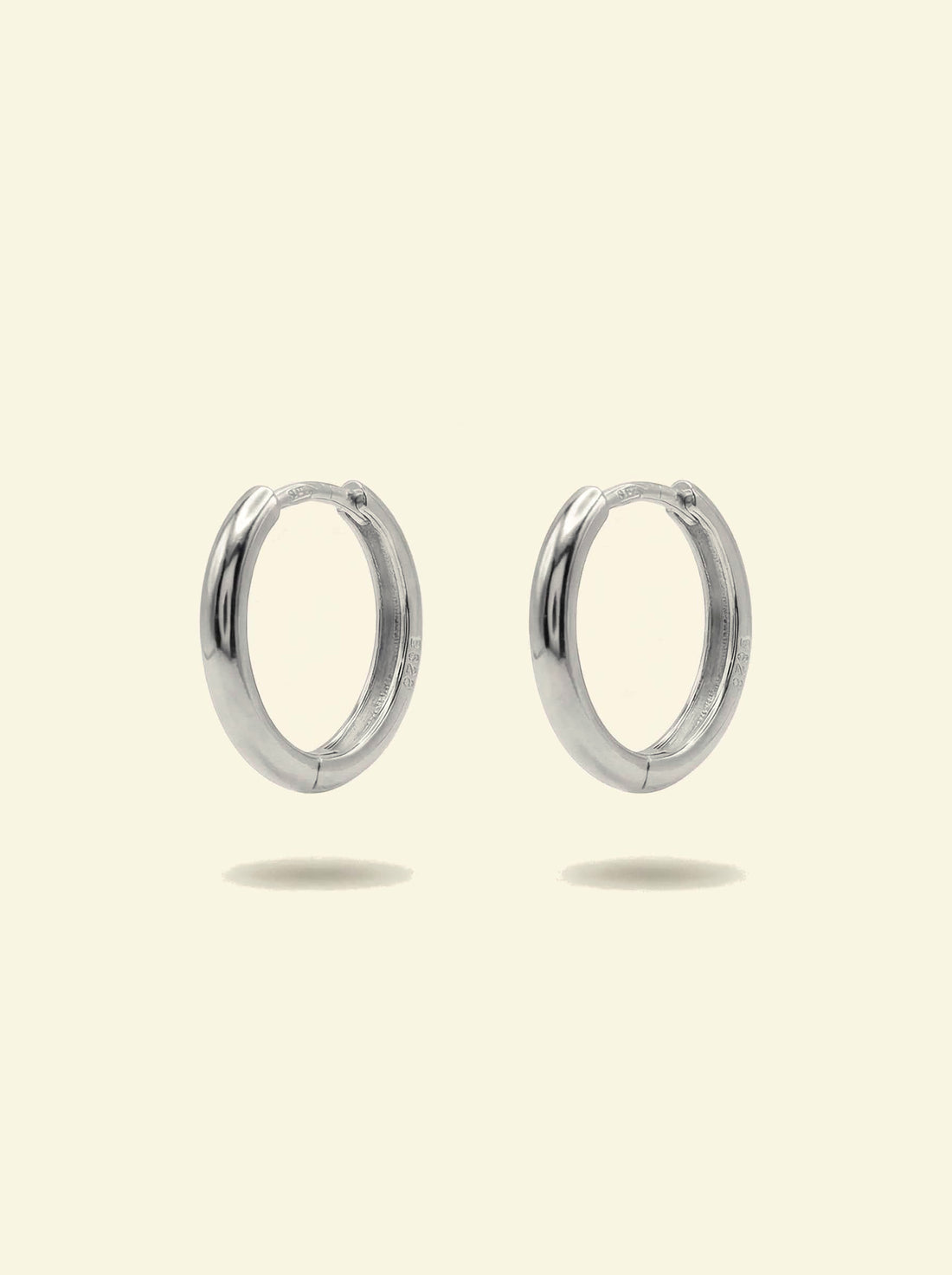 Classic Hoops, pair of smooth silver-tone huggie hoops standing upright, front 3/4 view