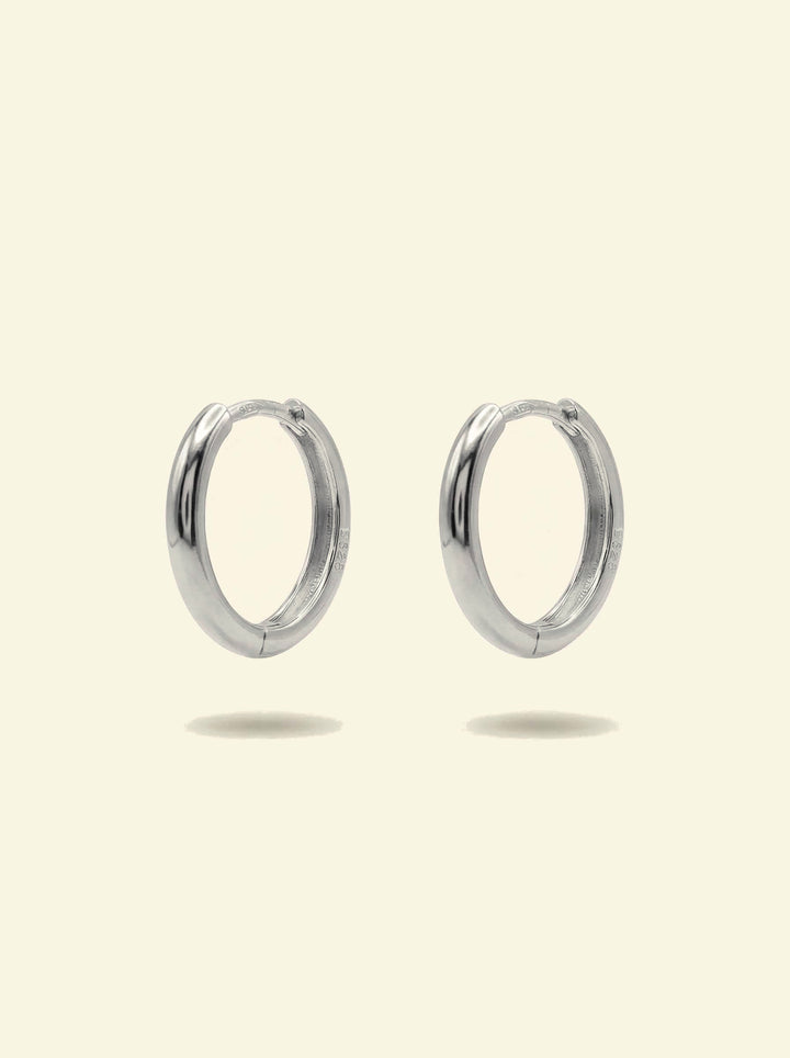 Classic Hoops, pair of smooth silver-tone huggie hoops standing upright, front 3/4 view