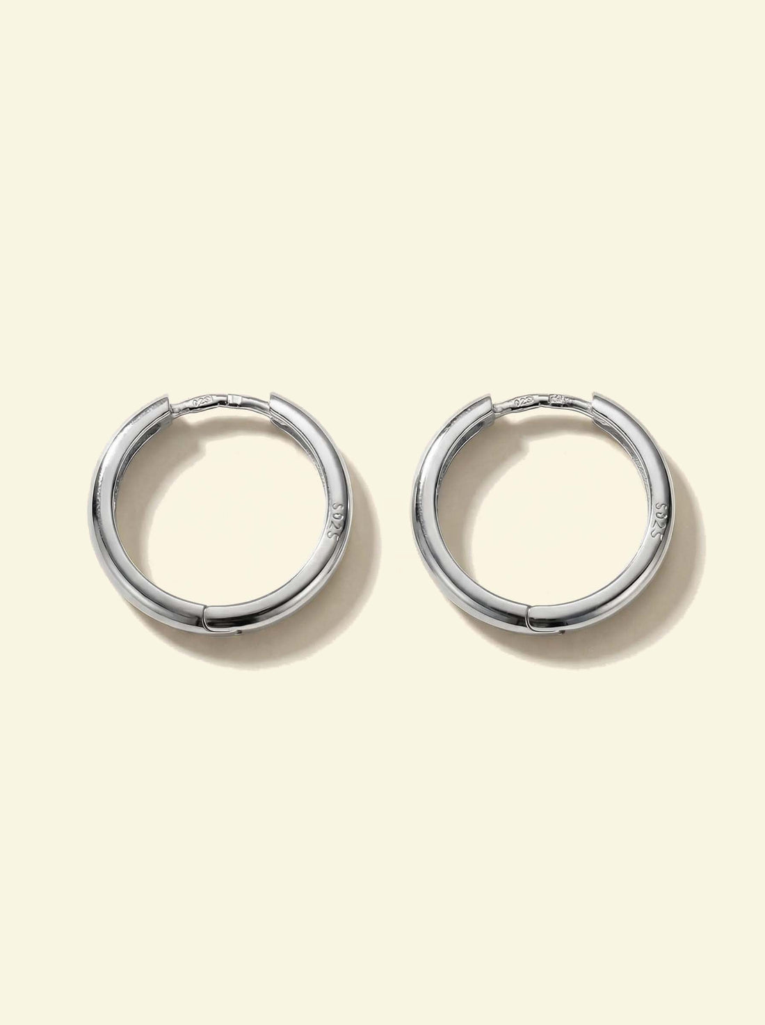 Classic Hoops, pair of smooth silver-tone hoops lying flat, face-on with S925 stamp visible