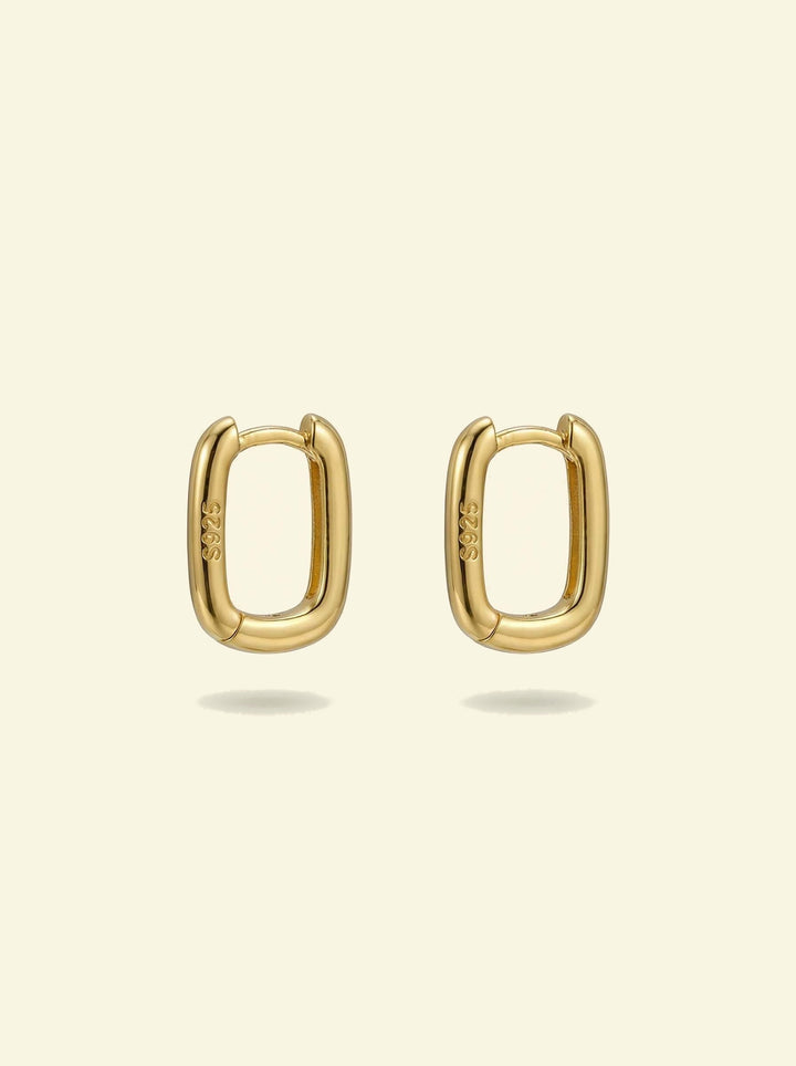 Link Mini Ovals, pair of small gold-tone oval hoop earrings with S925 stamp, front view on a cream background