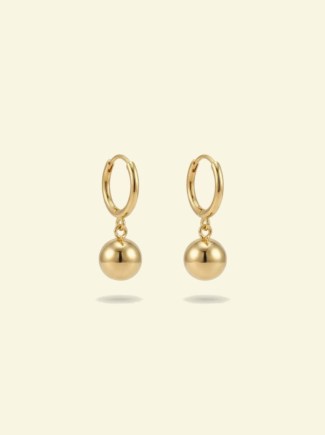 Dawn Drops, pair of small gold-tone huggie hoops with polished ball drops, front view