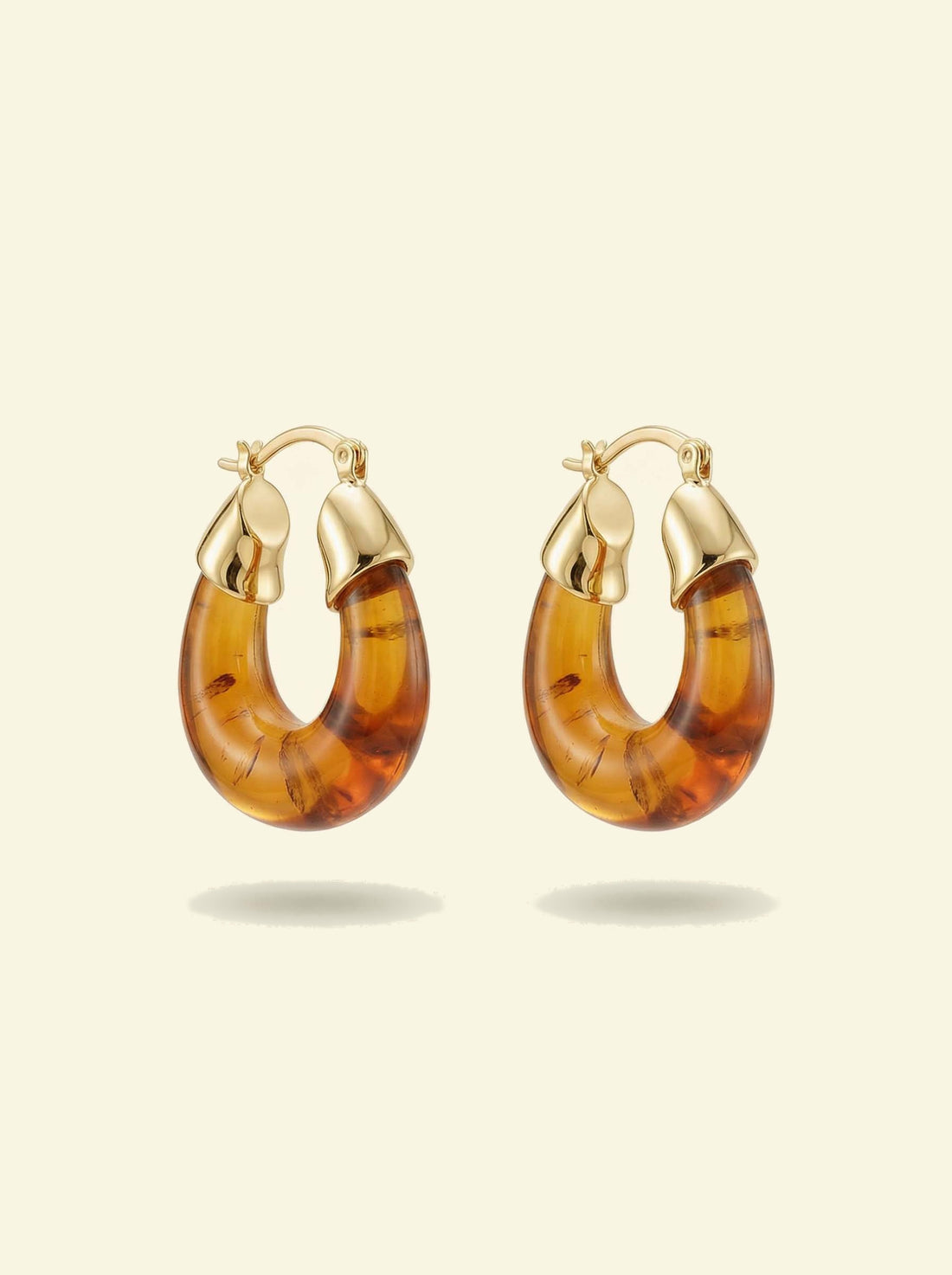 Ember Hoops, pair of translucent amber-coloured hoops with gold-tone caps and hinged clasps, front view