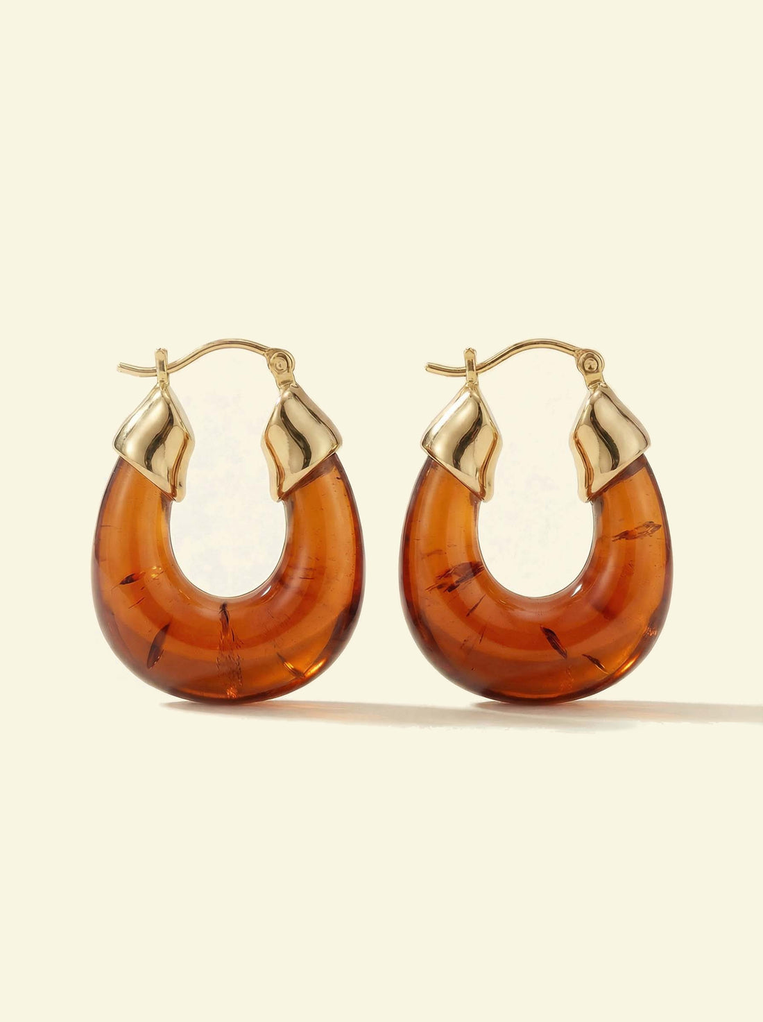 Ember Hoops, pair of translucent amber-coloured hoops with gold-tone caps showing darker inclusions, front view