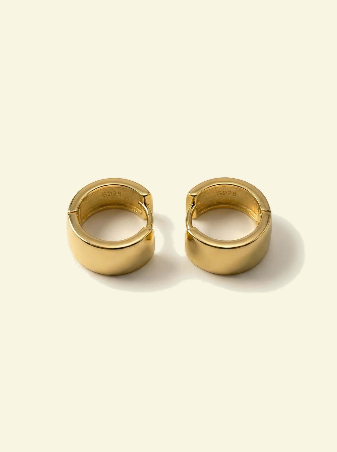 Forge Hoops, pair of gold-tone hoops lying flat with the S925 stamp visible inside the band