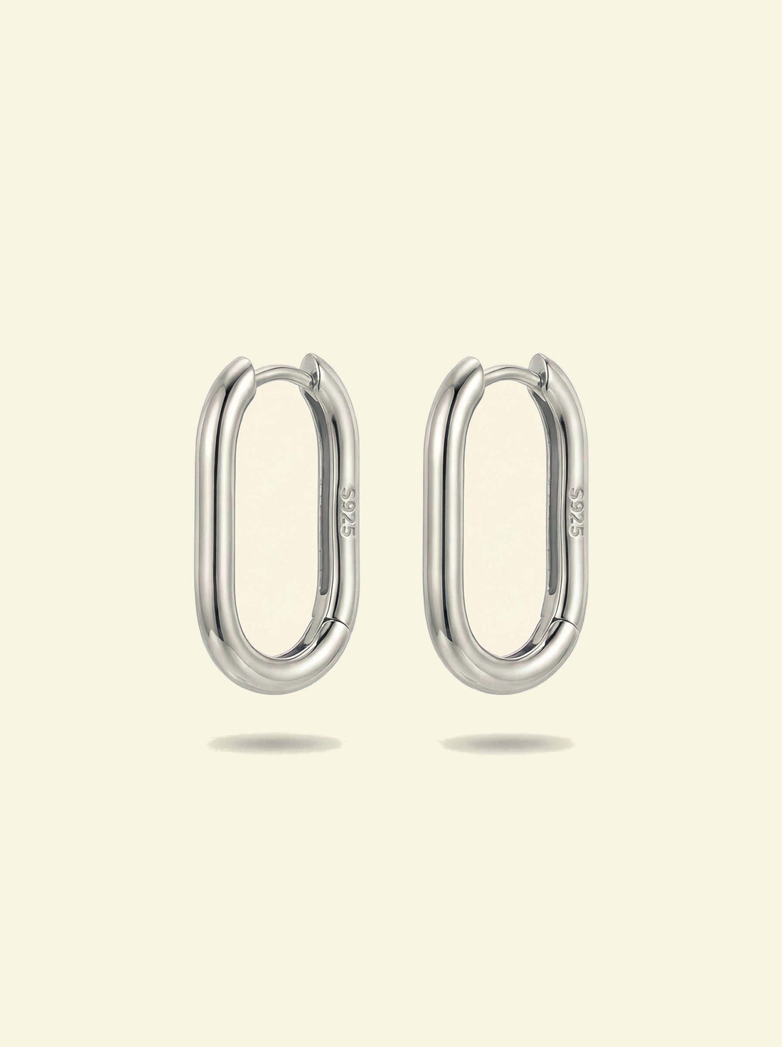 Link Large Ovals, pair of silver-tone oval hoop earrings with S925 stamp, front view on a cream background