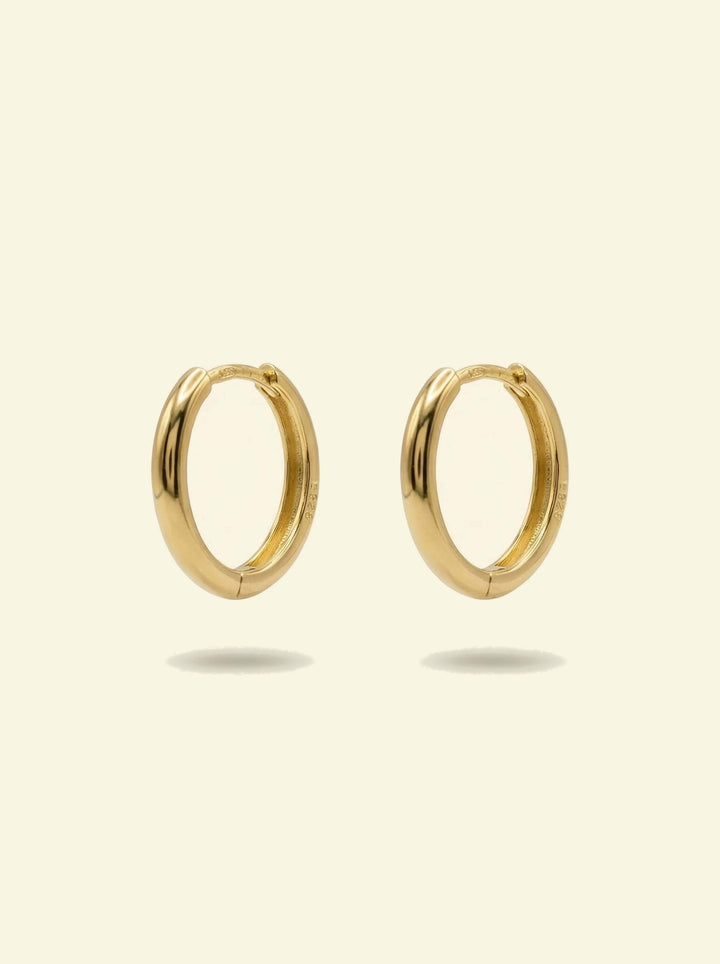 Classic Hoops, pair of smooth gold-tone huggie hoops standing upright, front 3/4 view