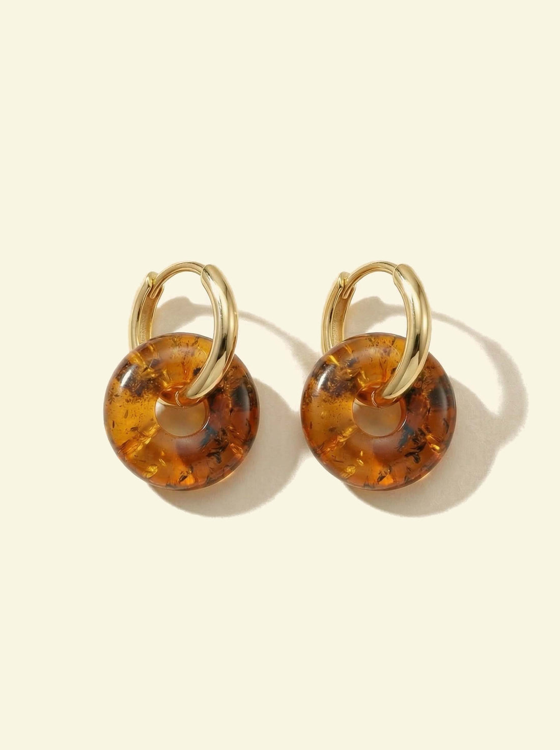 Nida Amber Hoops, pair of gold-tone hoops with amber-coloured discs, flat view with long soft shadows
