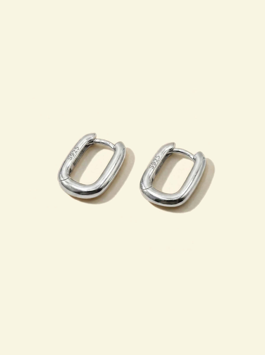 Link Mini Ovals, pair of small silver-tone oval hoops lying at an angle, S925 stamp visible