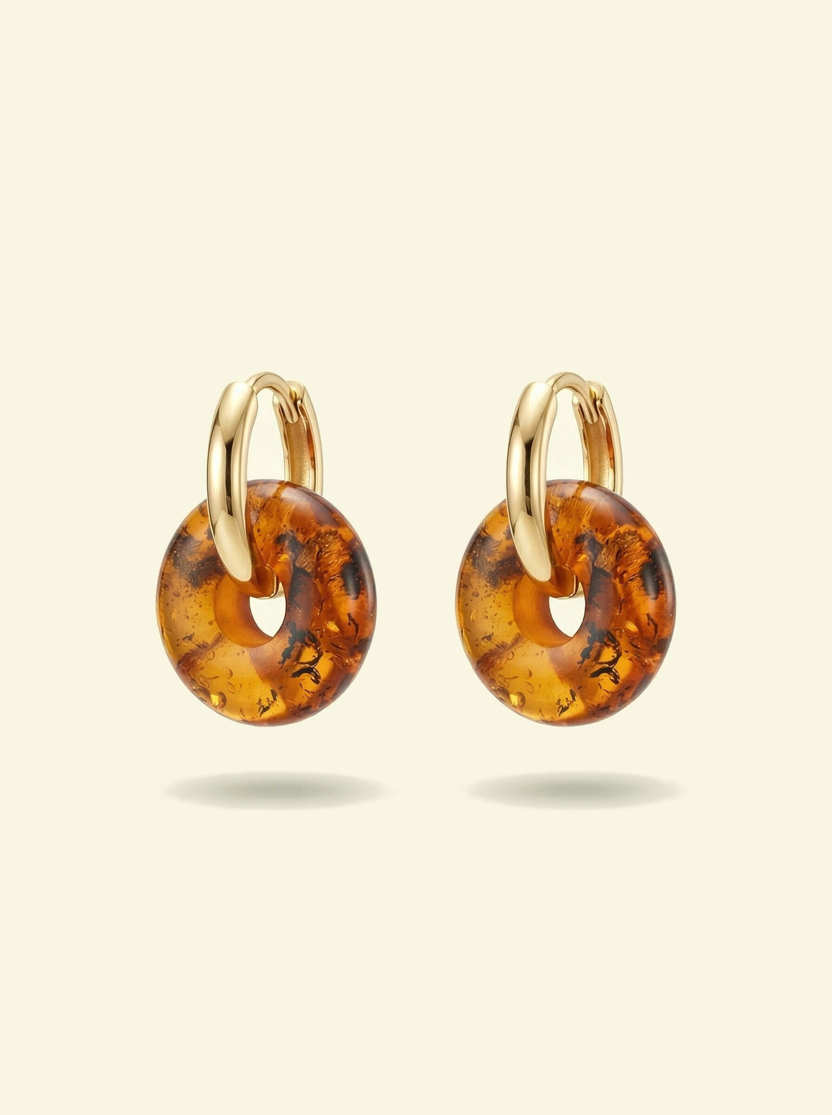 Nida Amber Hoops, pair of gold-tone huggie hoops with amber-coloured donut discs, hoops seen from the side