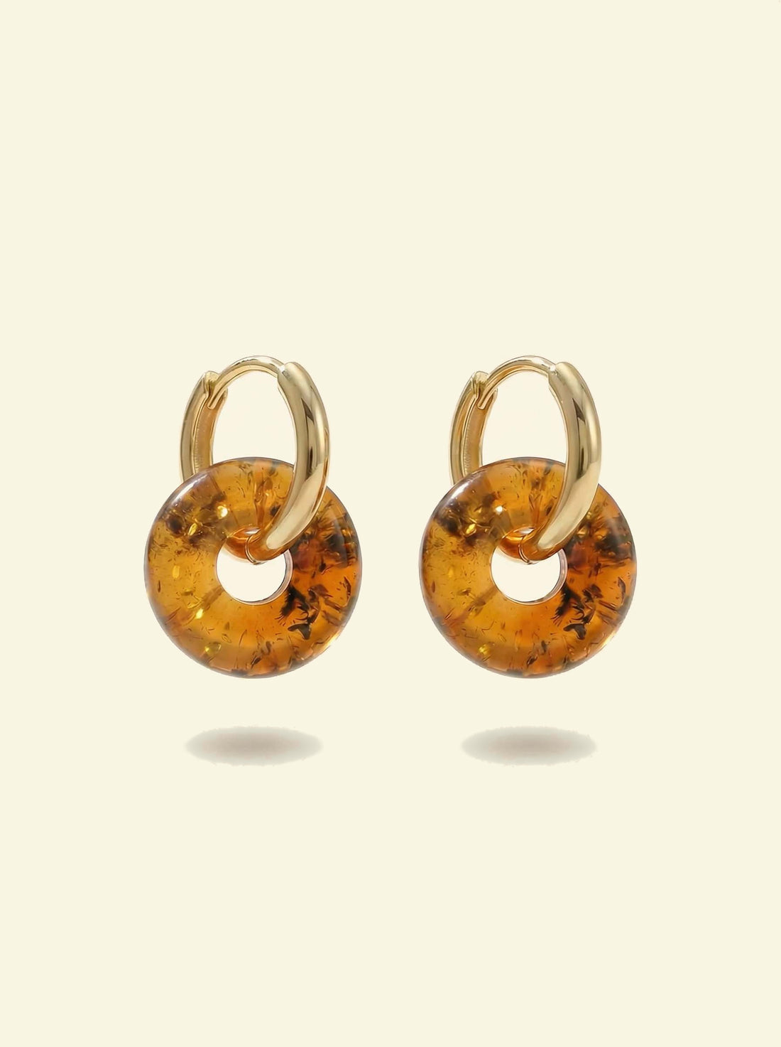 Nida Amber Hoops, gold-tone huggie hoops with mottled amber-coloured discs hanging below, hoops seen face-on