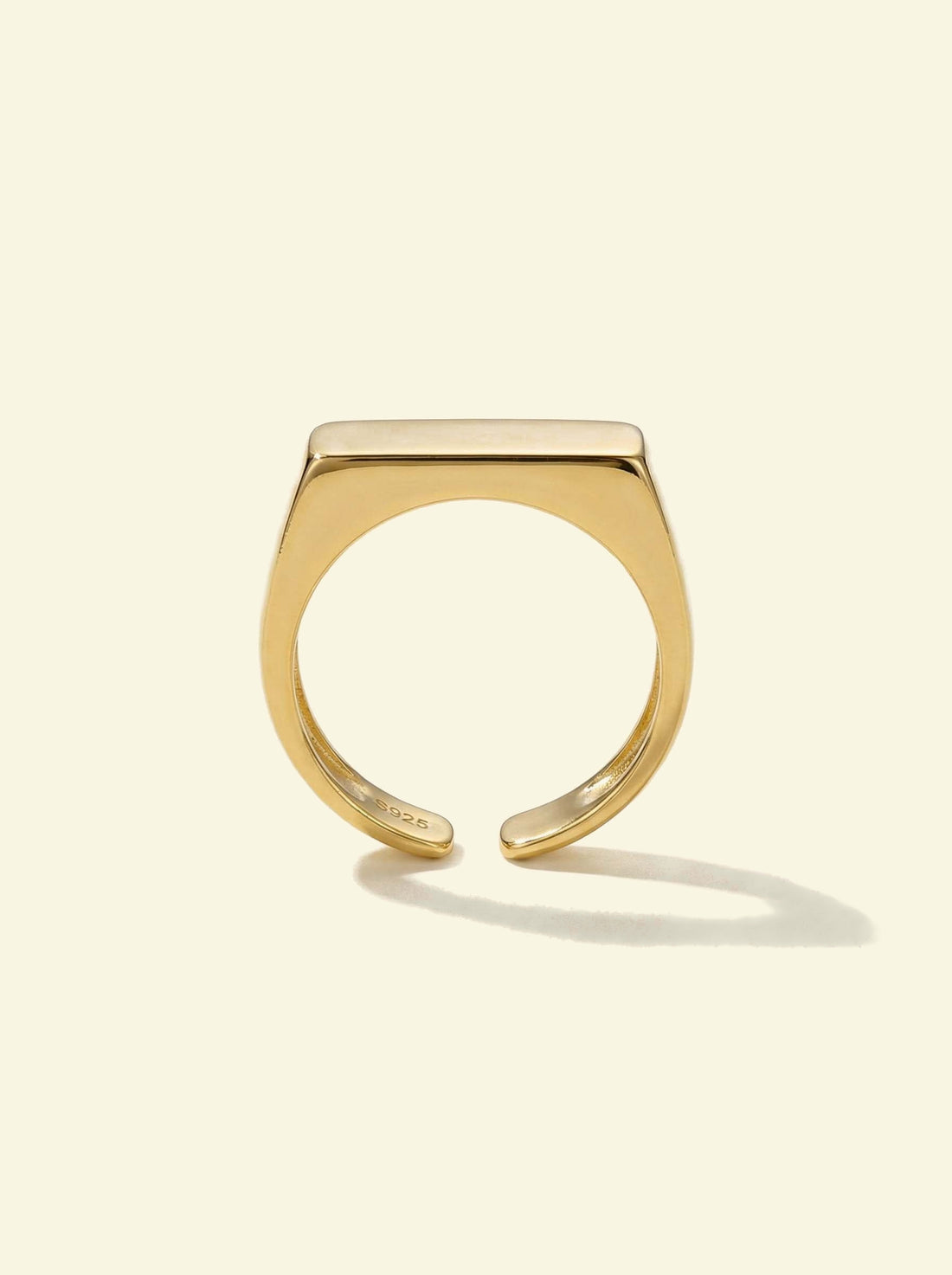 Preila Ring, gold-tone open band with a flat top, upright front view with a long shadow