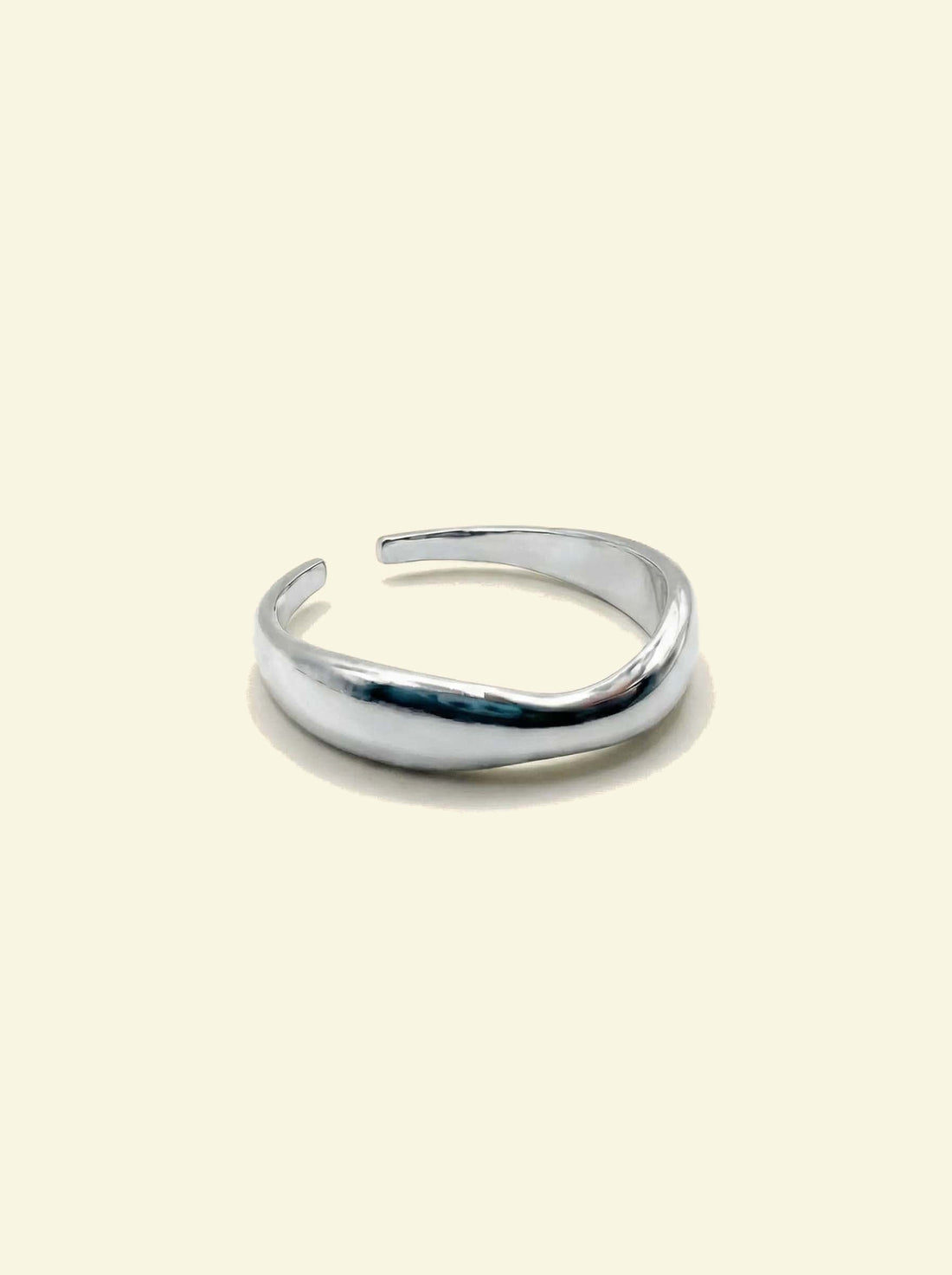 River Ring, silver-tone open wavy band, three-quarter view on a cream background