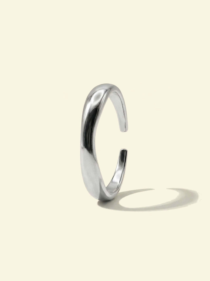 River Ring, silver-tone open wavy band standing upright, side view with a long shadow