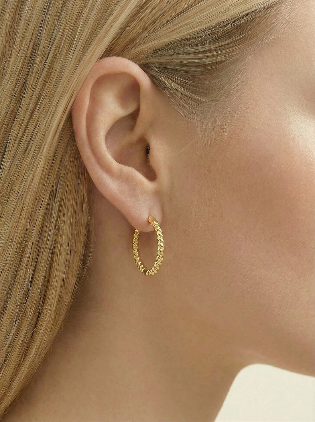 Sol Hoops, gold-tone twisted rope hoop worn in a woman's ear, side profile