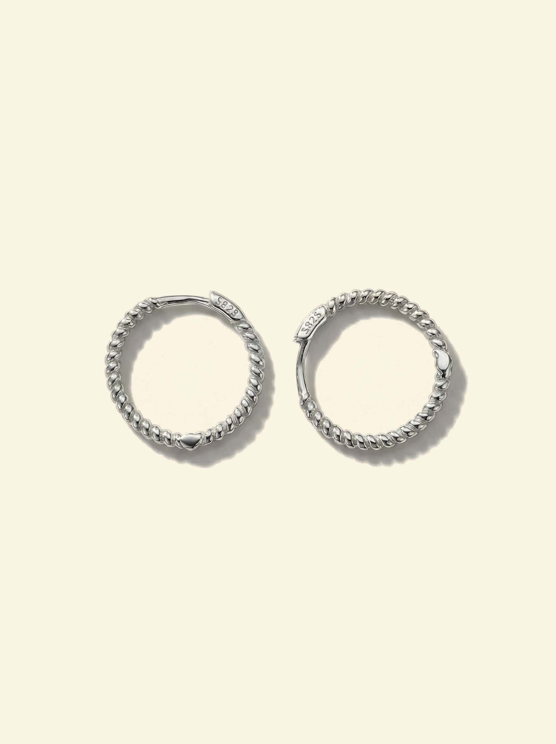Sol Hoops, pair of silver-tone twisted rope hoops lying flat, one turned to show the S925 clasp