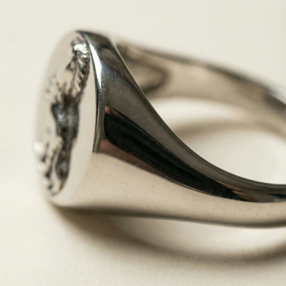 Close-up of a polished sterling silver signet ring with an engraved crest
